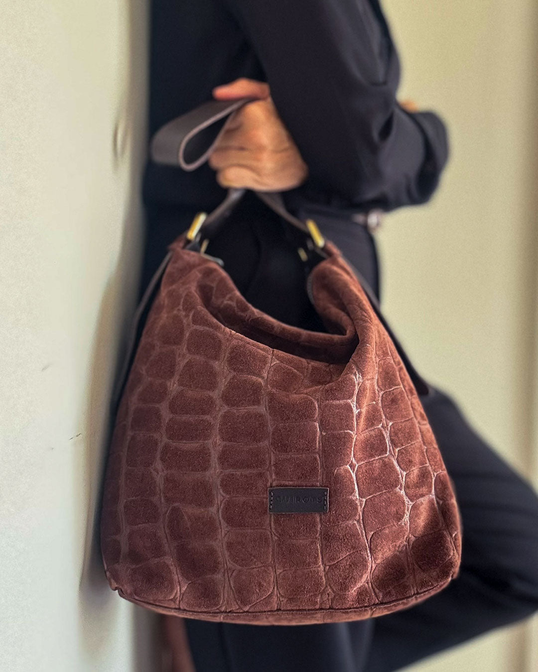 Bolso de hombro Coco de serraje en color testa, sujetado por el asa de piel