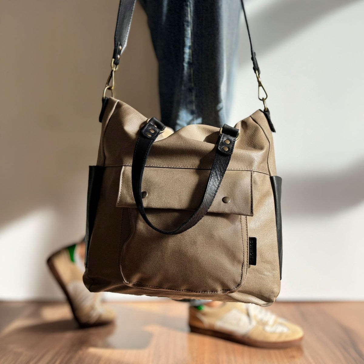 Bolso de mano y bandolera Barbour en color taupe, colgado de la mano