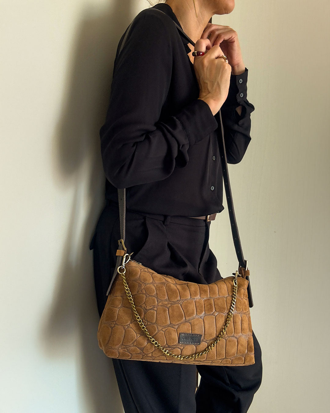 Bolso de hombro y bandolera Coco de serraje en color camel, con asa de cadena, llevado cruzado con camisa negra