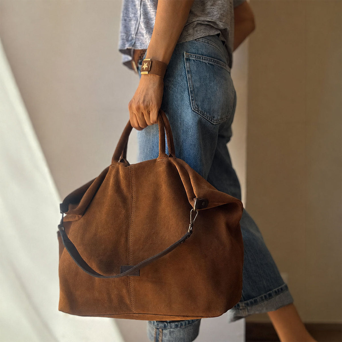 Bolso de mano grande Zoe de serraje en color cuero, llevado en la mano
