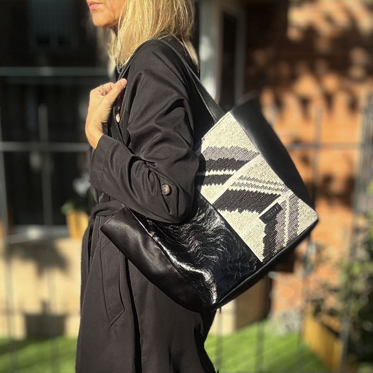 Shopper Jacquard de jacquard blanco y negro y piel negra, al hombro en un jardín